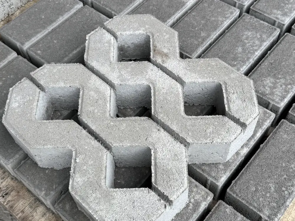 Dua grassblock lubang 5 tebal 8 cm di atas palet paving di area stok