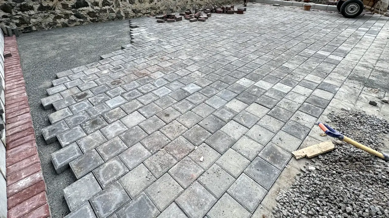 Pemasangan paving block Ubin K300 tebal 6 cm pola diagonal di atas lapisan abu batu, dengan border bata merah