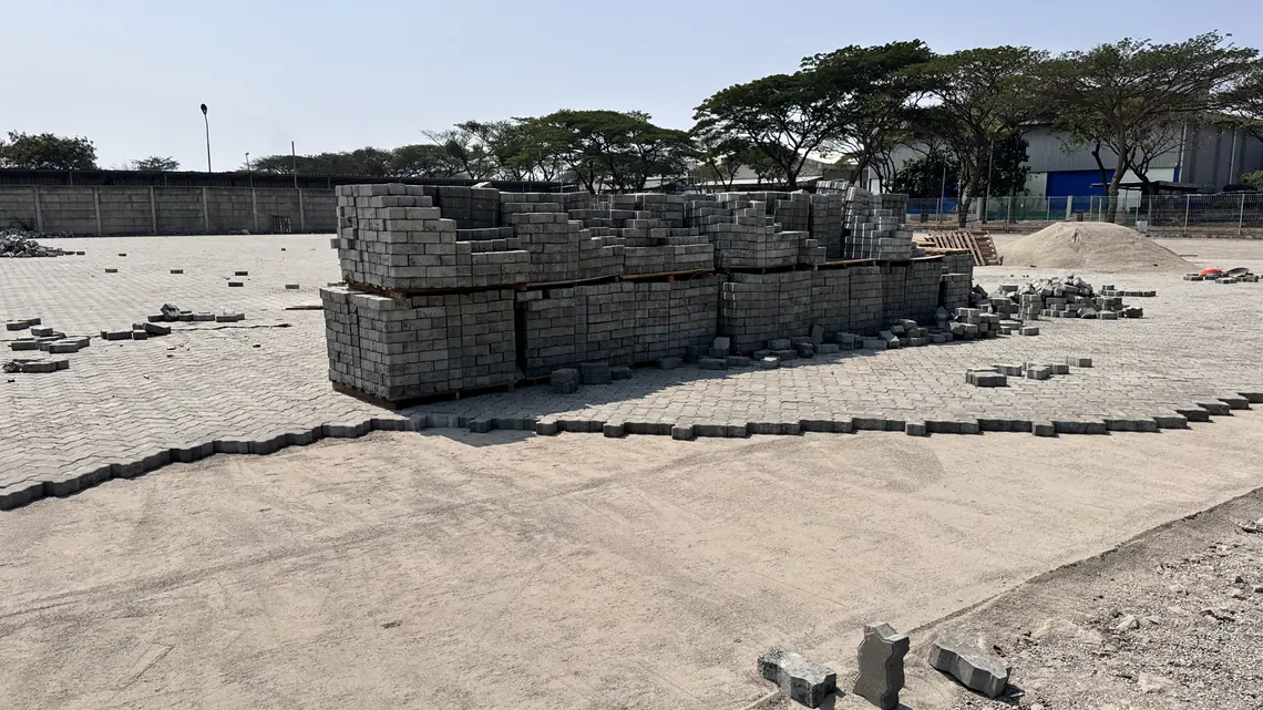 Progres pemasangan paving block cacing K400 di lahan container yard Marunda, material dipalet di atas area yang sudah terpasang