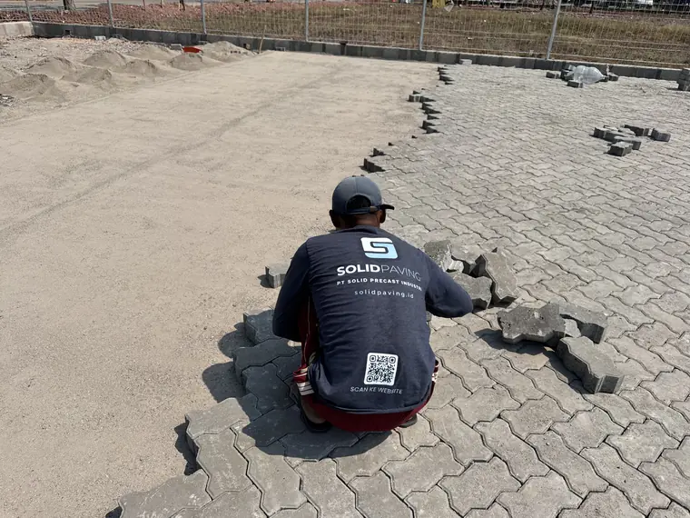 Tukang SolidPaving.id memasang paving block cacing K400 di atas pasir bedding yang sudah diratakan, Marunda